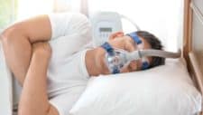 man in bed with cpap device for sleep apnea