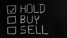 Hold, buy and sell written on chalk board with 'hold' ticked