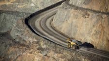 aerial view of dump truck full of dirt driving along road in open cut mine