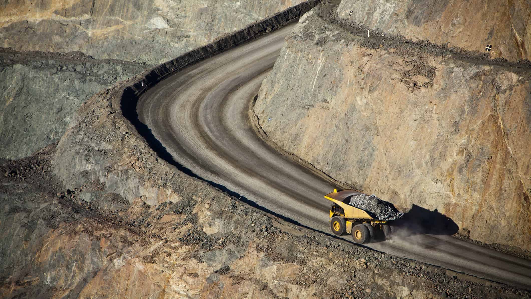 aerial view of dump truck full of dirt driving along road in open cut mine