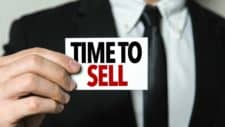 business man holding sign stating time to sell