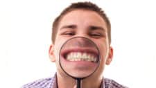 man smiling through magnifying glass