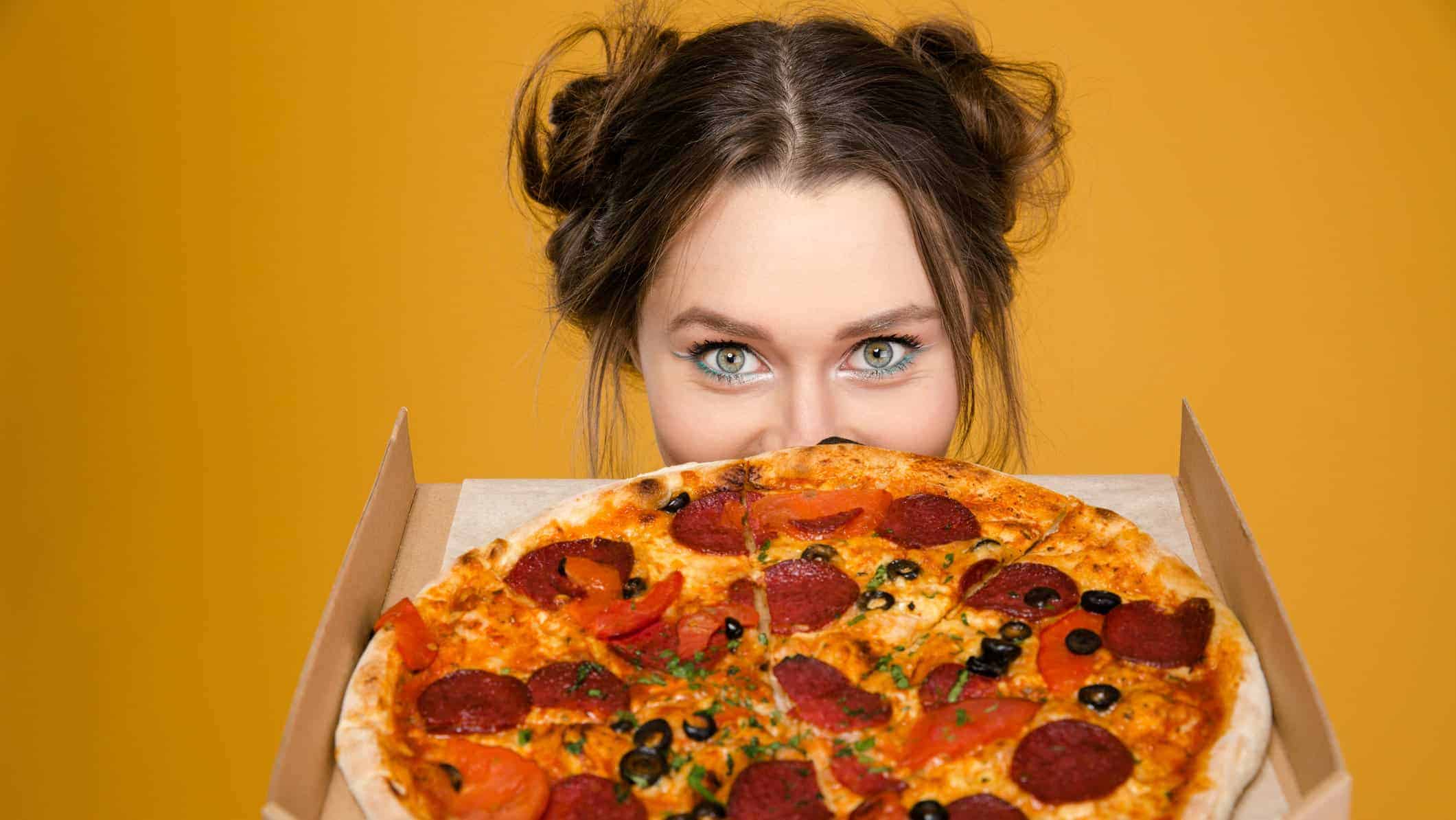 Woman holding Domino's pizza up to her face and looking excited about the company's latest news
