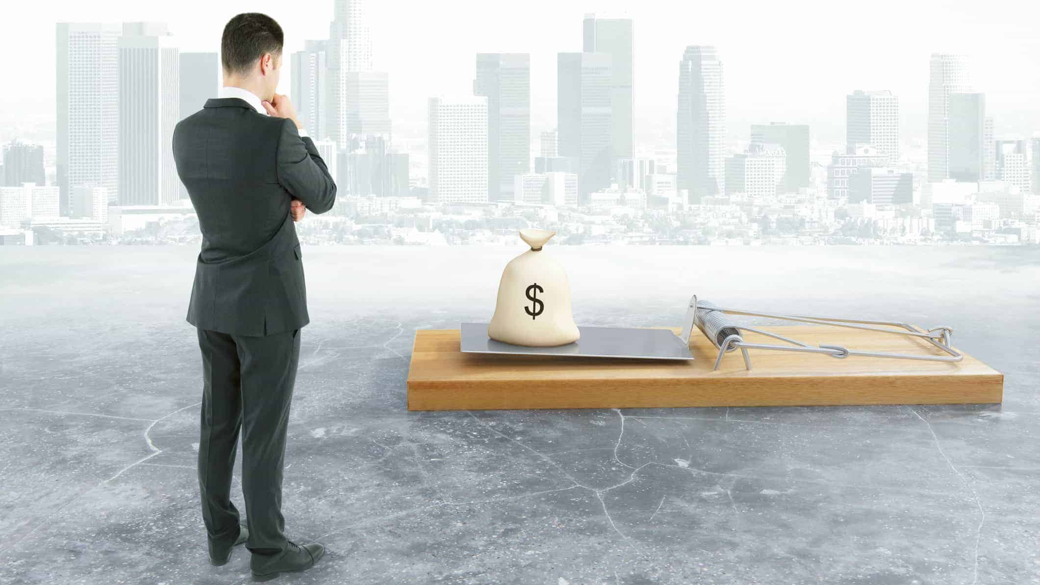 Investor looking at a pile of money in a large mousetrap to symbolise an ASX share dividend trap