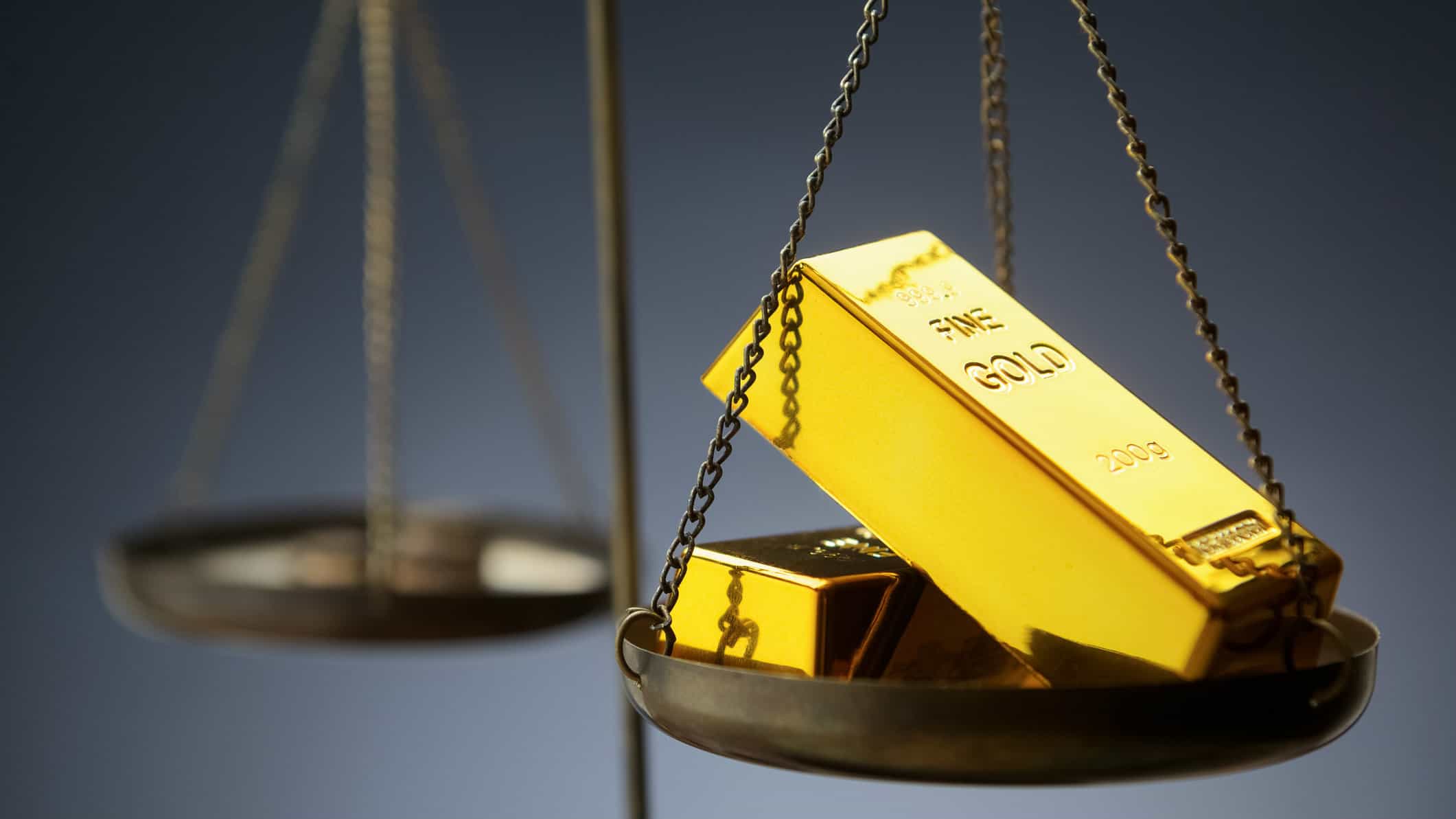 Old fashioned scales weighing two gold bars in front of dark background, gold share price, newcrest mining share price