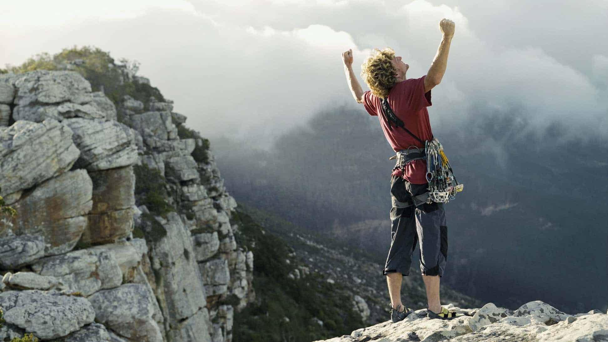 At climber at the top of a mountain, indicating a share price on the ASX that has hit a record high