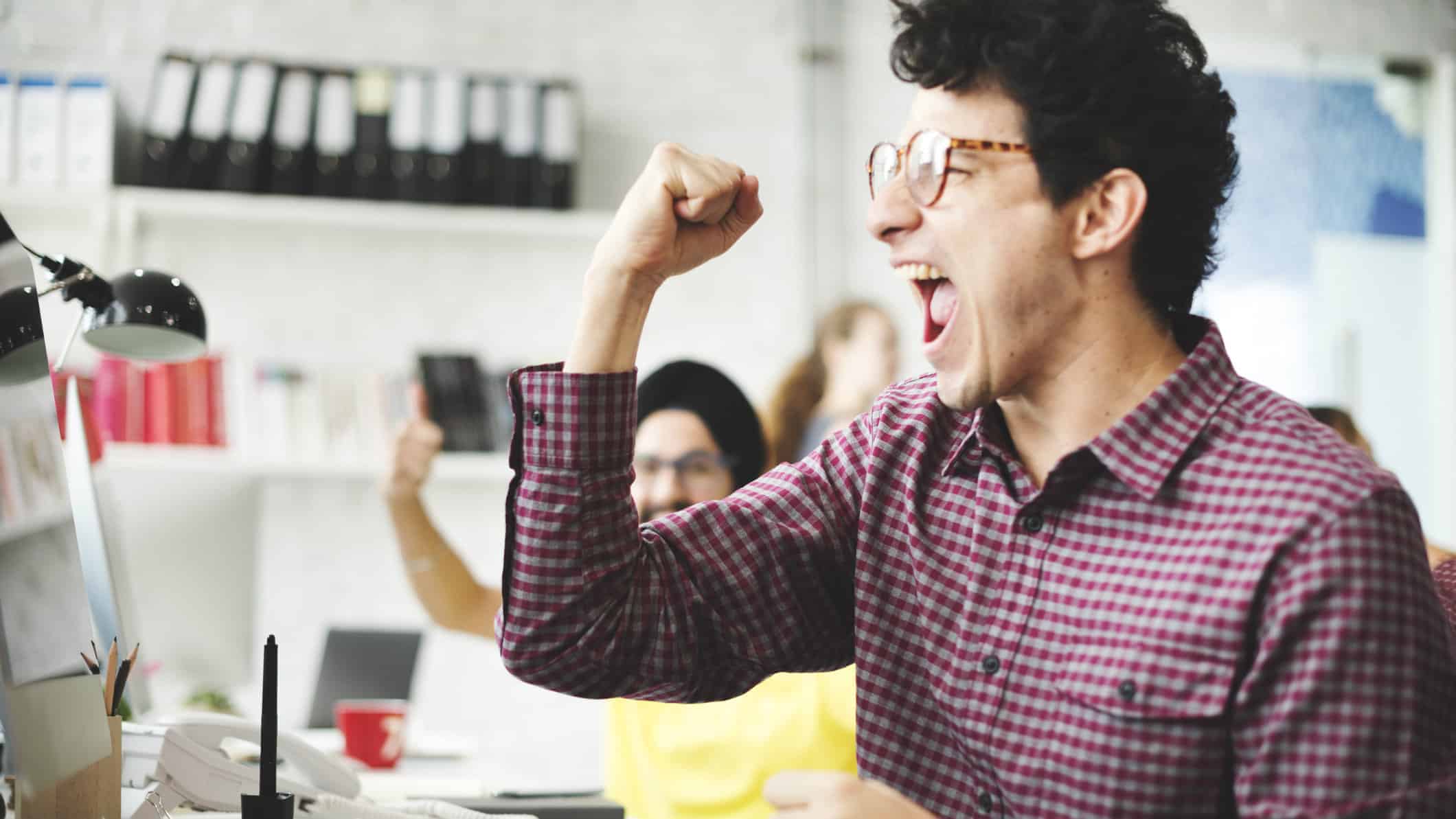 A man raises his arm in excitement, indicating a new ASX share price high