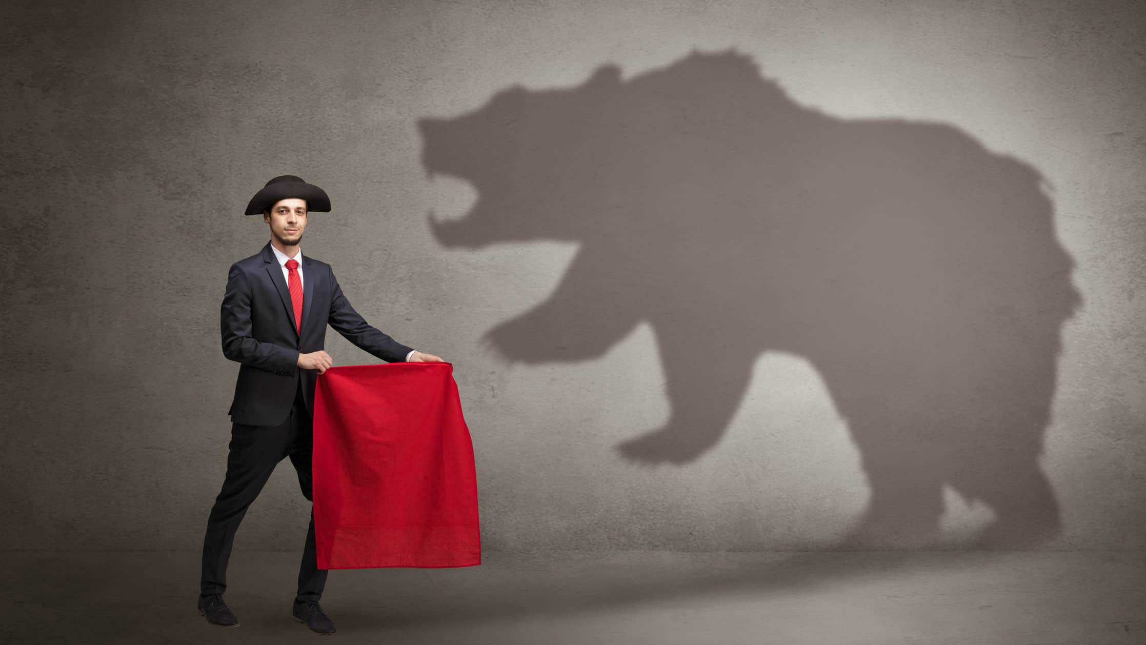 Broker holding red flag in front of bear
