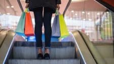 rising asx retail shares and REIT prices represented by woman on escalator carrying shopping bags