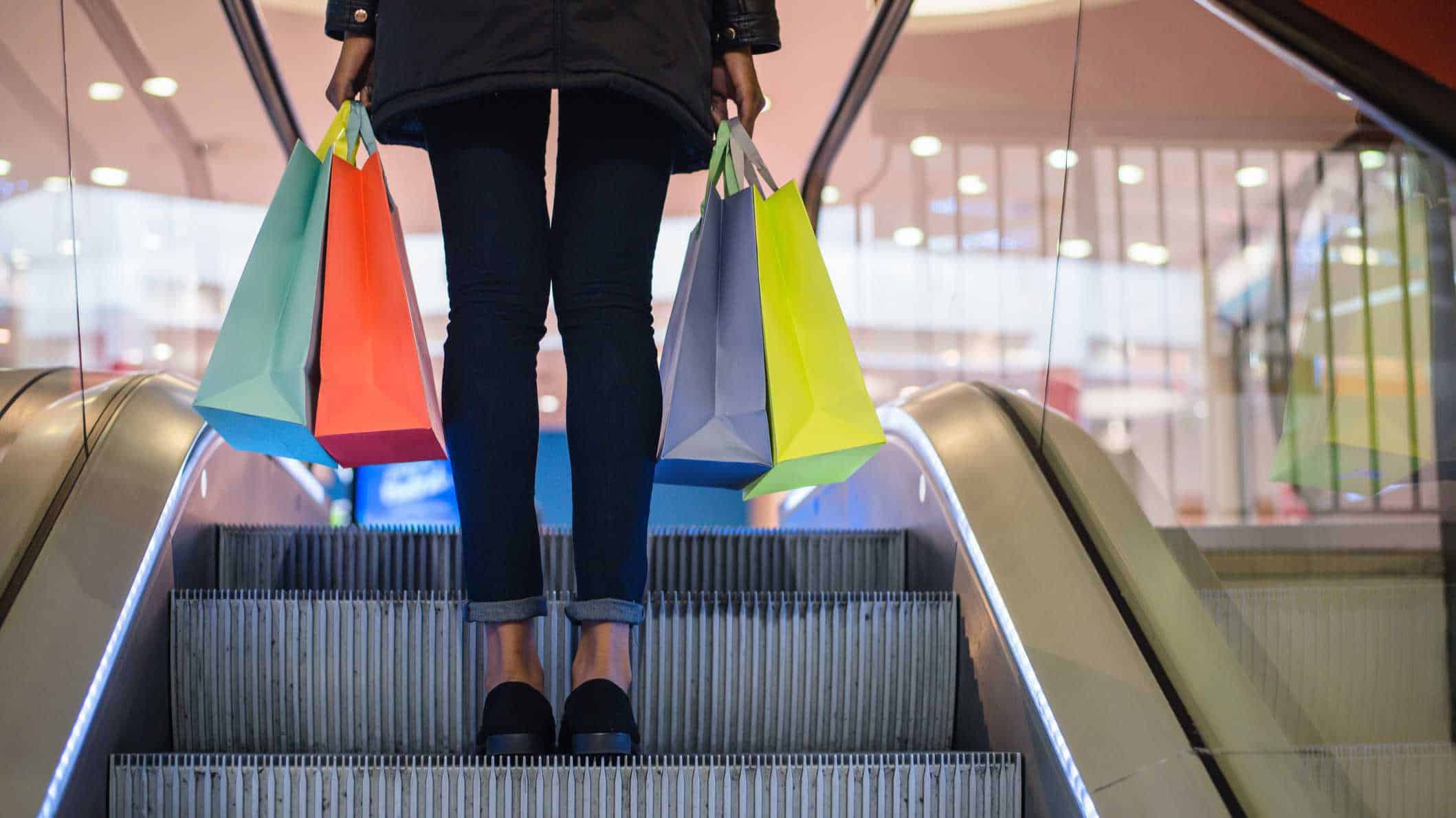 rising asx retail shares and REIT prices represented by woman on escalator carrying shopping bags