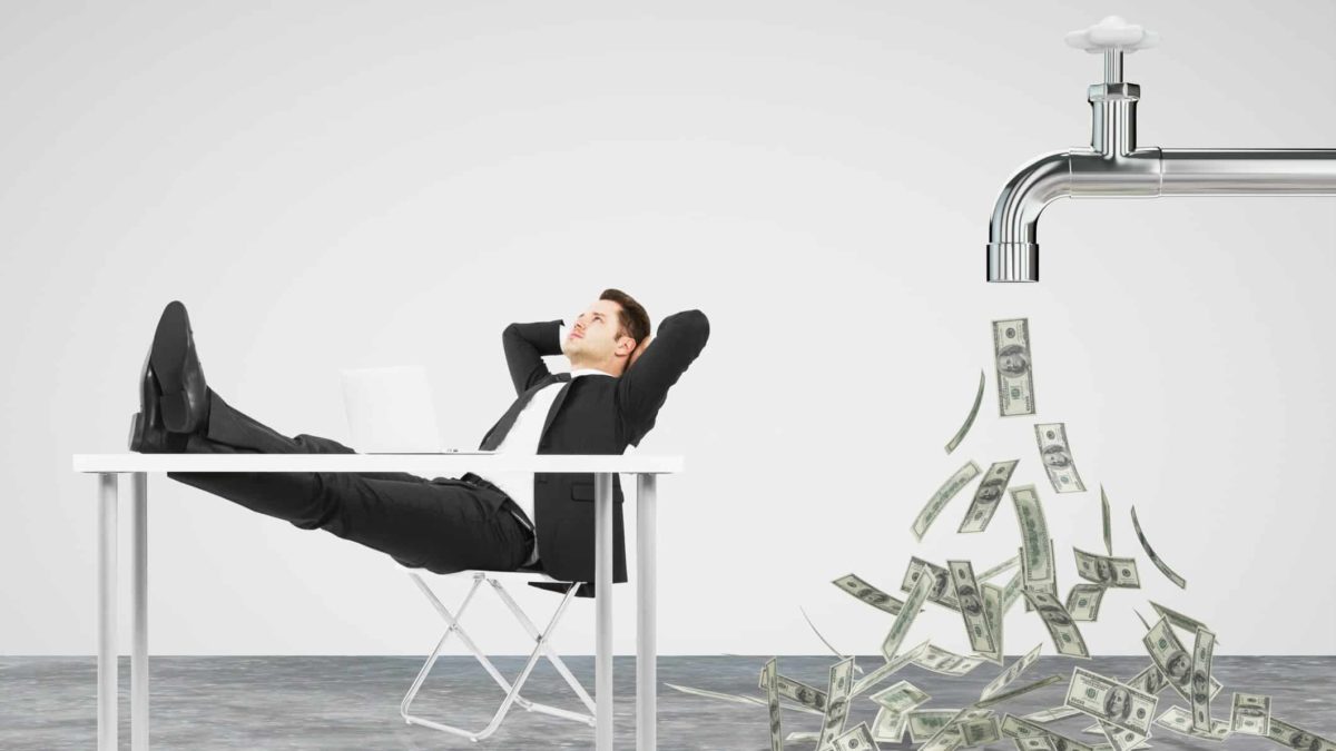 Man sitting back inna chair next to a large tap flowing with money.