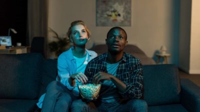Couple watching TV eating popcorn