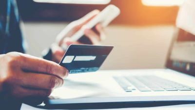 Online shopper holding credit card in front of laptop