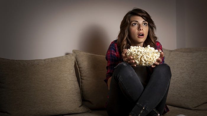 portrait of woman holding popcorn watching a movie