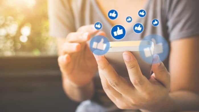 woman holding smartphone with social media symbols