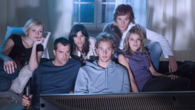 Group of young adults around a TV watching Netflix