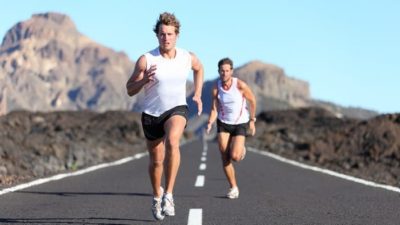 Two male runners racing down an empty road
