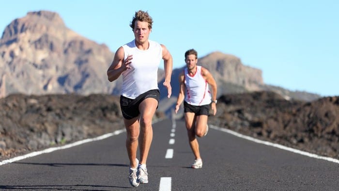 Two male runners racing down an empty road