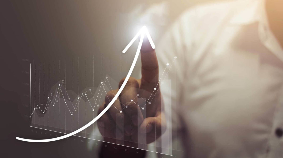 Pointing to an upward trend in data on screen.