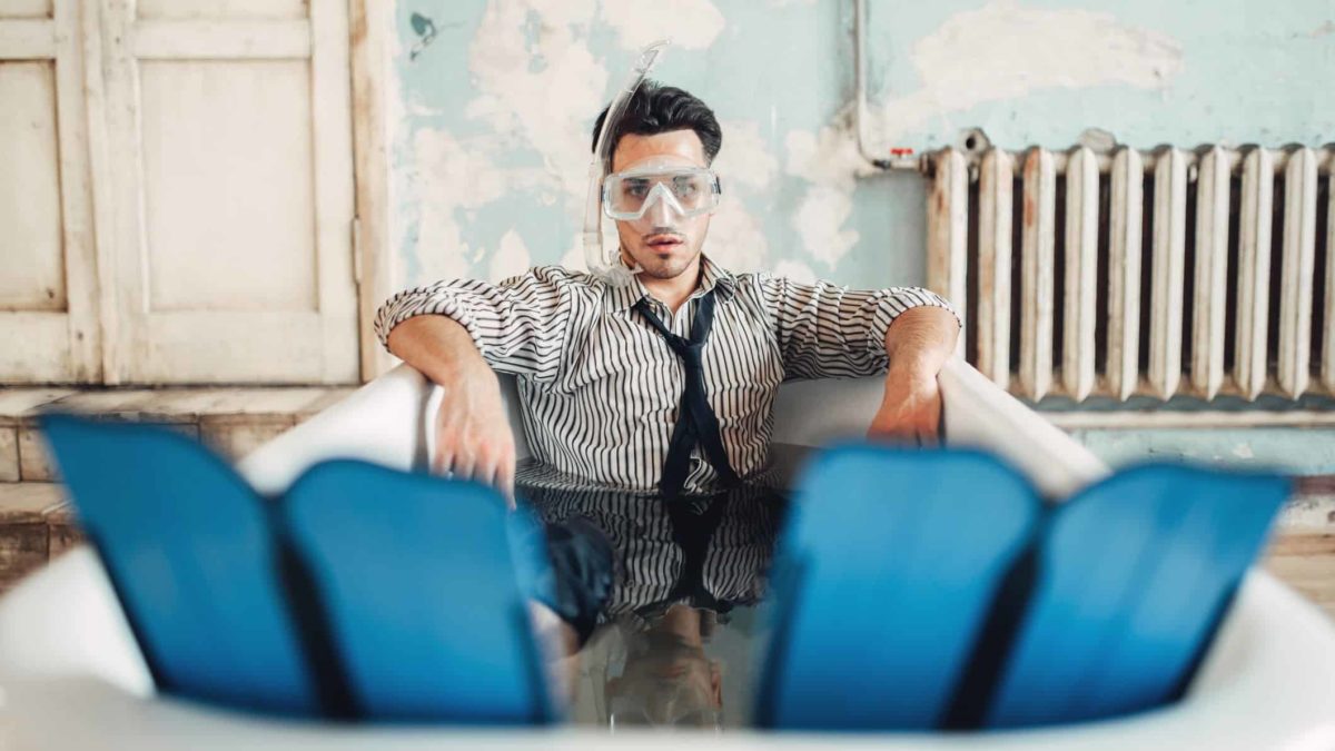 Man in business attire sitting in bath with snorkel and fins
