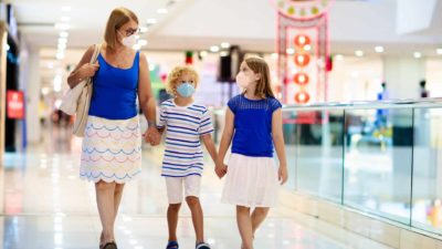 Family wearing protective face masks while visiting shopping centre reflecting ASX retail shares