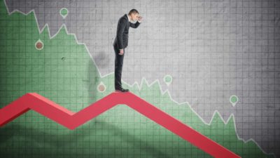 man looking down falling line chart, indicating a falling share price