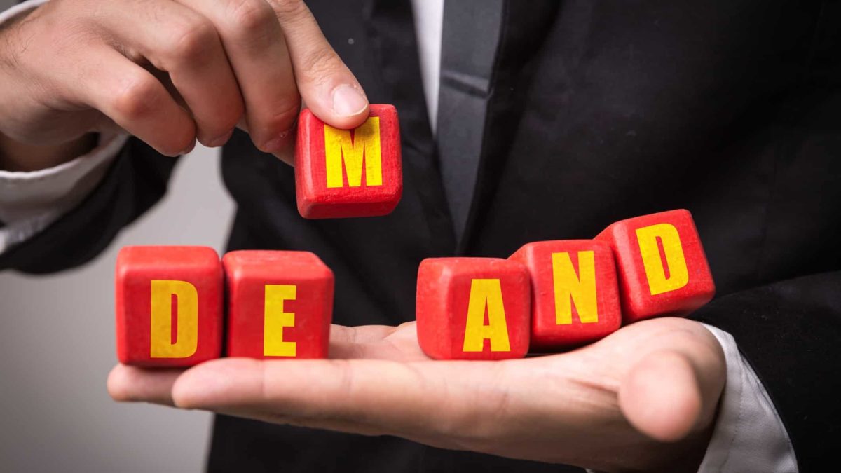 Businessman with block letter spelling out 'demand' resting on his palm