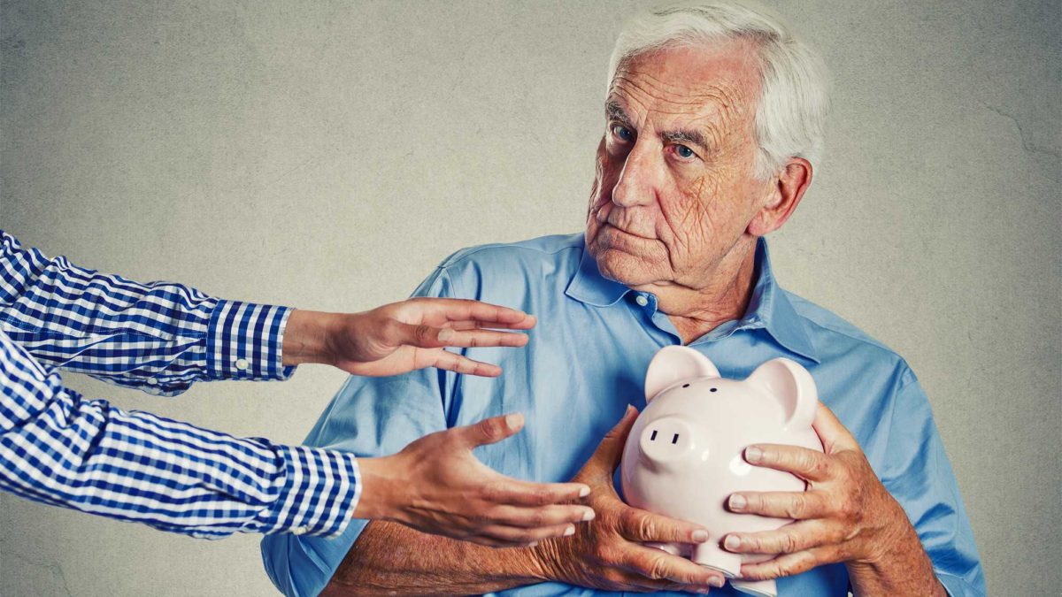 senior man holding piggy away from reaching hands