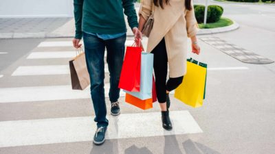 two people walking along carrying shopping bags