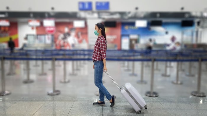 lady walking through empty airport to travel indicating tough times for asx 200 travel shares