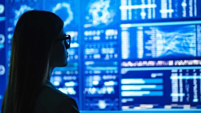 Female investor looking at a wall of share market charts