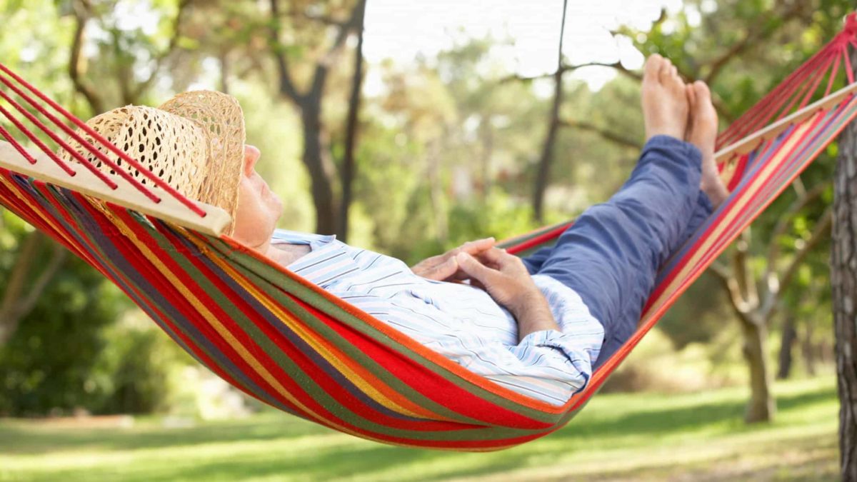 Retired man reclining in hammock with feet up, retire early