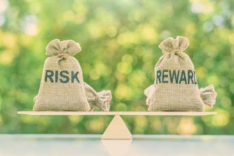 A seasaw-style scale in balance with two sandbags either end one labelled Risk and one labelled Reward