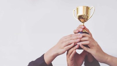 hands holding up winners cup, asx 200 winning shares