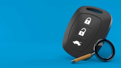 Car key and magnifying glass on blue background to signal car shares