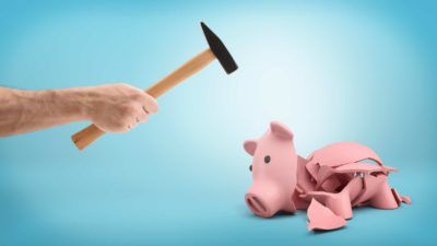 hand holding hammer smashing open empty piggy bank