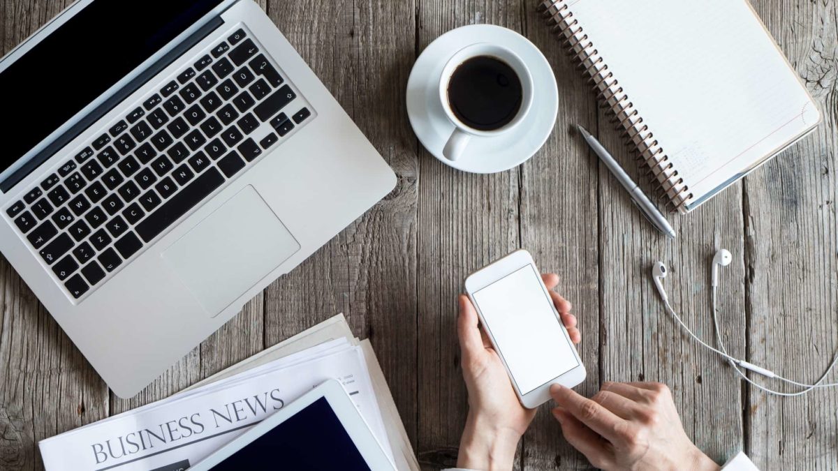 laptop, newspaper, ipad, coffee and hands holding iphone