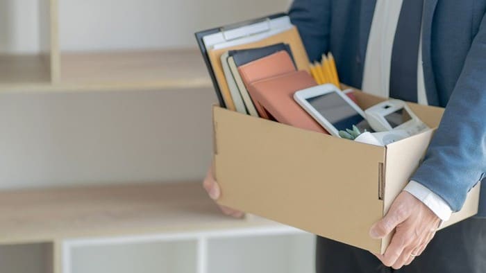 Man in business suit carries box of personal effects