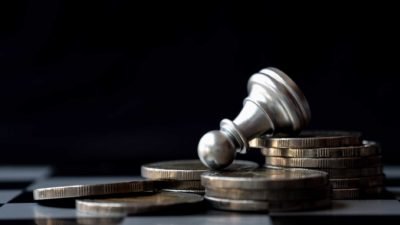 Toppled chess piece on top of pile of coins