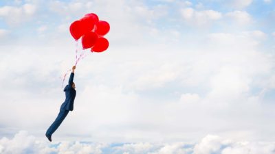 asx share price rise represented by man holding bunch of balloons soaring through the air