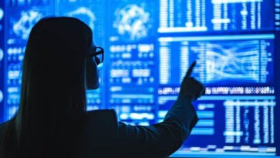 qoman standing in front of digital screen pointing