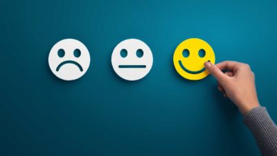 hand selecting happy face from choice of happy, sad and neutral faces signifying best ASX shares