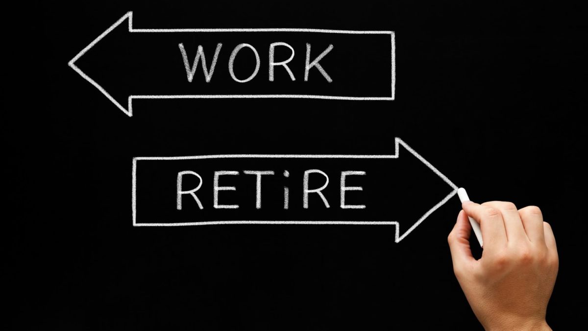 hand drawing two arrows on chalk board with one saying work and the other saying retire