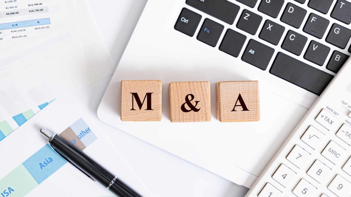 laptop, pens, calculator and wooden blocks spelling m and a