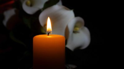 lit candle against backdrop of flowers representing propel funeral partners share price