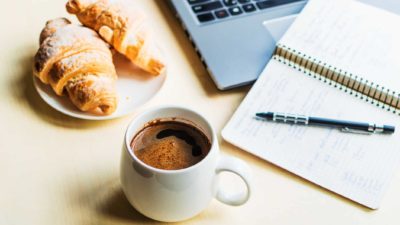 coffee and pastries next to note pad and laptop computer