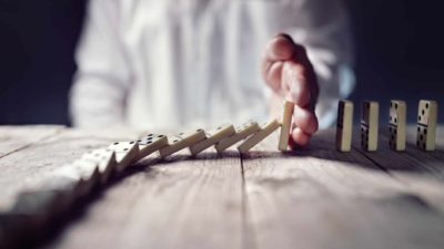 man placing hand to try to stop falling dominos representing afterpay and sezzle share prices