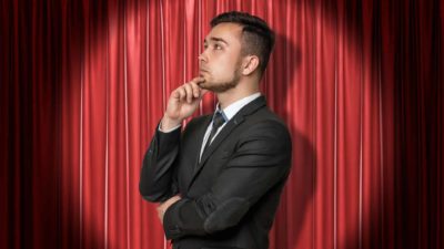 asx share stage set for advance represented by business man in spotlight in front of red curtain