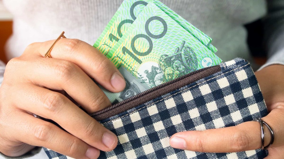 woman putting hundred dollar notes into purse