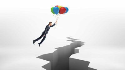 man holding bunch of balloons floating across large crack in ground representing asx shares to avoid